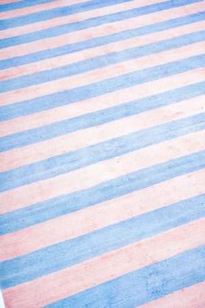 Linear pattern alternating between light blue and pink on a kilim rug by Carpet Cellar