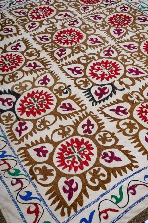 Off-white hand embroidered textile with brown and pink patterns by Carpet Cellar