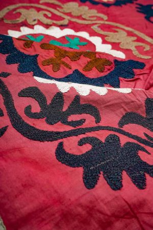 Pink hand embroidered textile with dark blue and beige patterns by Carpet Cellar