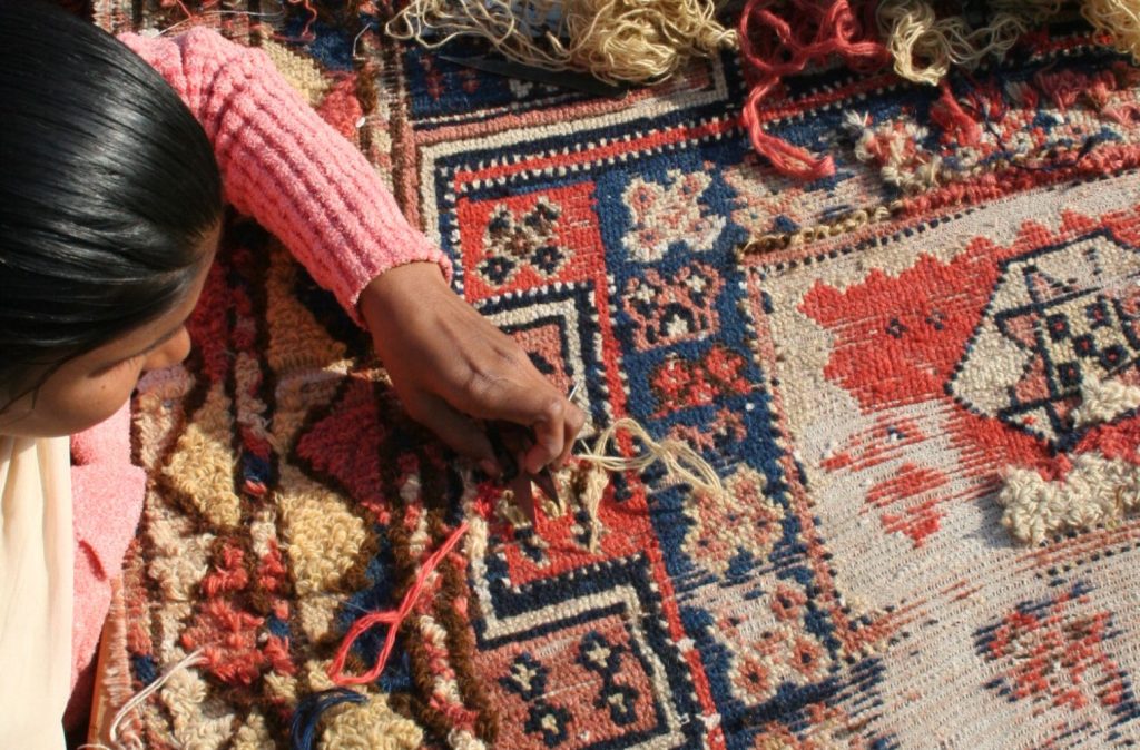 Woman artisan restoring a rug at Carpet Cellar